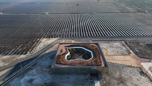 Aerial view of the Karapinar Solar Power Plant featuring vast arrays of photovoltaic panels and a modern central building with a green courtyard in Karapinar Konya Turkey.