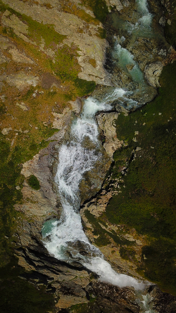 Aerial view of a rushing river carving its way through the rugged rocky landscape edged with green moss creating a mesmerizing display of nature s raw power Valgrisenche Aosta Valley Italy.