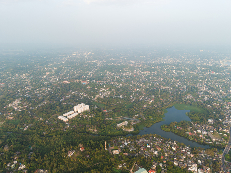 Aerial view of the lush tropical landscape with residential houses dense trees and a calm body of water under a hazy sky in Galle Southern Province Sri Lanka.