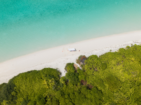 Aerial view of turquoise waters meeting the white sandy beach and dense green vegetation creating a vibrant contrast of colors Thuraakunu Thiladhunmathee Uthuruburi Maldives. Aerial view of turquoise waters meeting the white sandy beach and dense green vegetation creating a vibrant contrast of colors Thuraakunu Thiladhunmathee Uthuruburi Maldives.