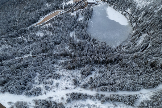 Aerial view of the frozen Mummelsee lake surrounded by a dense snow covered pine forest in the Black Forest region of Seebach Baden Wurttemberg Germany. Aerial view of the frozen Mummelsee lake surrounded by a dense snow covered pine forest in the Black Forest region of Seebach Baden Wurttemberg Germany.
