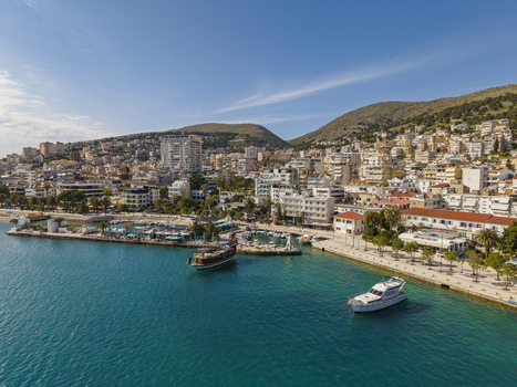 Aerial view of Saranda harbor with yachts and boats docked along the promenade surrounded by coastal hills and urban buildings in Saranda Vlore County Albania. Aerial view of Saranda harbor with yachts and boats docked along the promenade surrounded by coastal hills and urban buildings in Saranda Vlore County Albania.