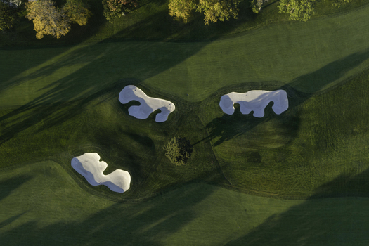 Aerial view of a golf course with sand bunkers and autumn trees casting long shadows on the green grass in Glenview Illinois United States. Aerial view of a golf course with sand bunkers and autumn trees casting long shadows on the green grass in Glenview Illinois United States.