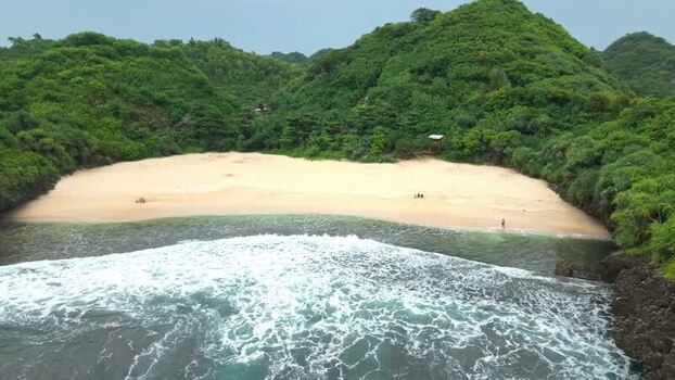 Aerial view of Sedahan Beach and lush green hills Indonesia.