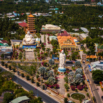 Aerial view of the Vinh Trang Pagoda complex featuring a large standing Buddha statue a reclining Buddha and a pagoda tower surrounded by lush gardens in Vietnam. Aerial view of the Vinh Trang Pagoda complex featuring a large standing Buddha statue a reclining Buddha and a pagoda tower surrounded by lush gardens in Vietnam.