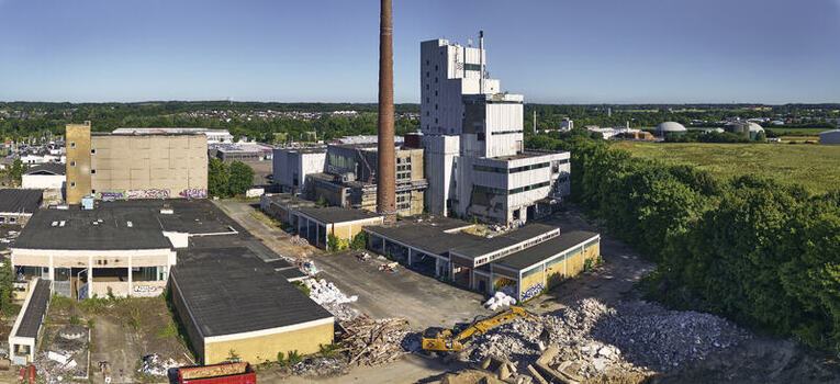Schleswig Germany 26 June 2026 Aerial view of the former Butterwerken butter factory demolition site with industrial buildings a tall brick chimney and construction machinery amidst debris. Schleswig Germany 26 June 2026 Aerial view of the former Butterwerken butter factory demolition site with industrial buildings a tall brick chimney and construction machinery amidst debris.