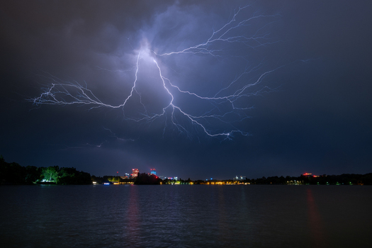 View of a powerful lightning strike illuminating the night sky over the city skyline and lake in Bucharest Bucharest Romania. View of a powerful lightning strike illuminating the night sky over the city skyline and lake in Bucharest Bucharest Romania.