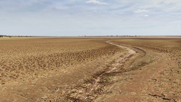 Aerial view of a vast drought stricken landscape with parched earth and a dry riverbed stretching across the arid plains in Beaufort West Western Cape South Africa. Aerial view of a vast drought stricken landscape with parched earth and a dry riverbed stretching across the arid plains in Beaufort West Western Cape South Africa.