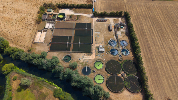 Aerial view of a wastewater treatment works with circular settling tanks and rectangular aeration basins situated next to a river and agricultural fields in St Neots England United Kingdom. Aerial view of a wastewater treatment works with circular settling tanks and rectangular aeration basins situated next to a river and agricultural fields in St Neots England United Kingdom.