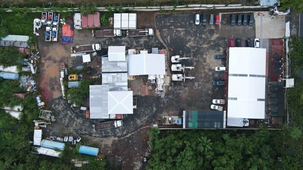 Aerial view of the Bambu Apus construction site with heavy machinery parked trucks and warehouse facilities on muddy ground in Kecamatan Cipayung Daerah Khusus Ibukota Indonesia. Aerial view of the Bambu Apus construction site with heavy machinery parked trucks and warehouse facilities on muddy ground in Kecamatan Cipayung Daerah Khusus Ibukota Indonesia.
