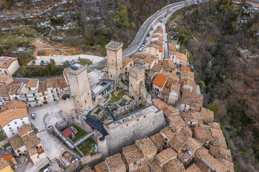 Aerial view of the medieval Caldora Castle with its three square towers and historic stone walls surrounded by terracotta rooftops in Pacentro Abruzzo Italy. Aerial view of the medieval Caldora Castle with its three square towers and historic stone walls surrounded by terracotta rooftops in Pacentro Abruzzo Italy.