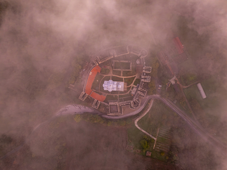 Aerial view of Manasija Monastery surrounded by thick morning fog and lush greenery in Despotovac Pomoravski okrug Serbia.