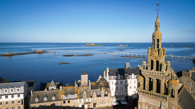 Aerial view of the old church steeple towers over the quaint town leading the eye to the expansive ocean and distant islands Roscoff Bretagne France. Aerial view of the old church steeple towers over the quaint town leading the eye to the expansive ocean and distant islands Roscoff Bretagne France.
