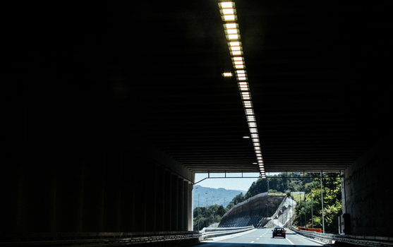 View of a car driving out of a tunnel into daylight with mountainous landscape in the background in Greece.