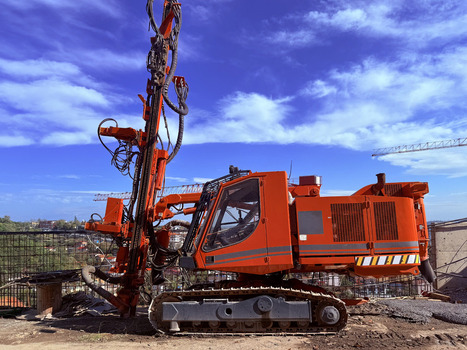 View of a large orange hydraulic drilling rig operating on a construction site under a blue sky with light clouds Beylikduzu Istanbul Turkiye. View of a large orange hydraulic drilling rig operating on a construction site under a blue sky with light clouds Beylikduzu Istanbul Turkiye.