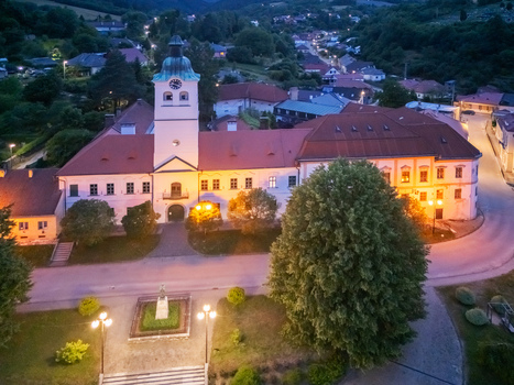 Aerial view of the illuminated Gelnica Town Hall its clock tower piercing the twilight sky amidst the town s quiet streets Gelnica Kosice Region Slovakia. Aerial view of the illuminated Gelnica Town Hall its clock tower piercing the twilight sky amidst the town s quiet streets Gelnica Kosice Region Slovakia.