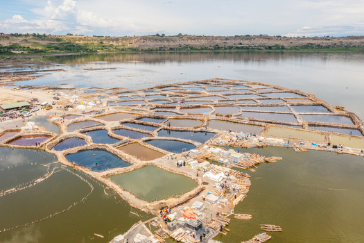 Aerial view of the colorful salt evaporation ponds at Lake Katwe with workers on wooden walkways in Kasese Western Region Uganda.
