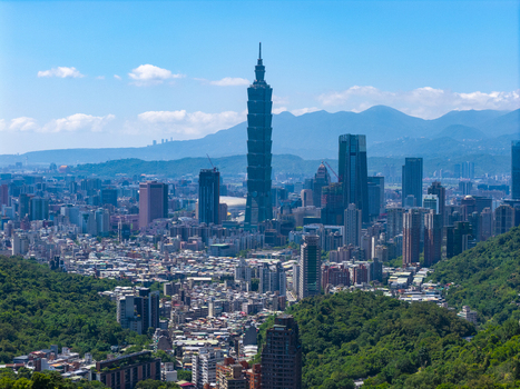 Aerial view of Taipei 101 skyscraper rising above the dense urban skyline surrounded by lush green hills under a clear blue sky in Taipei Taipei City Taiwan. Aerial view of Taipei 101 skyscraper rising above the dense urban skyline surrounded by lush green hills under a clear blue sky in Taipei Taipei City Taiwan.