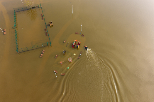 Aerial view of a flooded playground and sports court with a small boat navigating through the brown water in Kedainiai Kaunas County Lithuania. Aerial view of a flooded playground and sports court with a small boat navigating through the brown water in Kedainiai Kaunas County Lithuania.