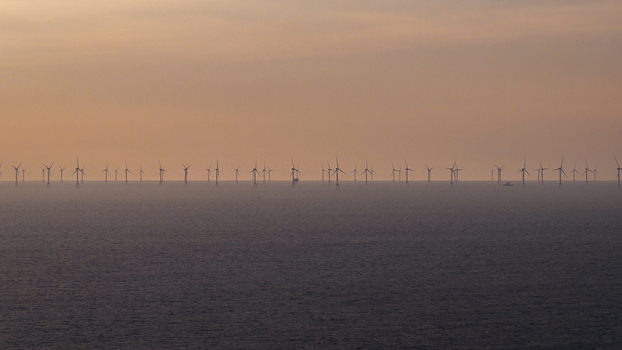 Aerial view of offshore wind turbines in the Atlantic Ocean during a golden sunset off the coast of Plevenon Brittany France. Aerial view of offshore wind turbines in the Atlantic Ocean during a golden sunset off the coast of Plevenon Brittany France.