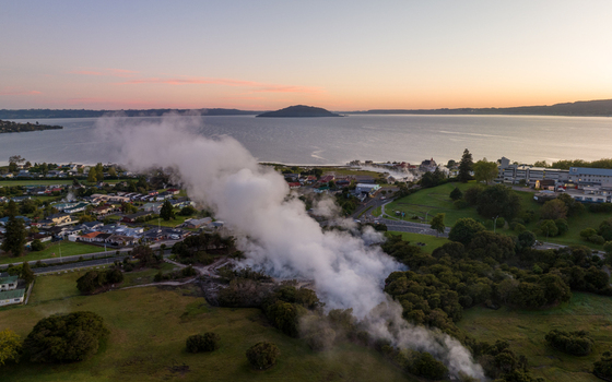 Aerial view of steam rising from geothermal vents creating a misty veil over the town meeting the lake Rotorua Bay of Plenty Region New Zealand. Aerial view of steam rising from geothermal vents creating a misty veil over the town meeting the lake Rotorua Bay of Plenty Region New Zealand.