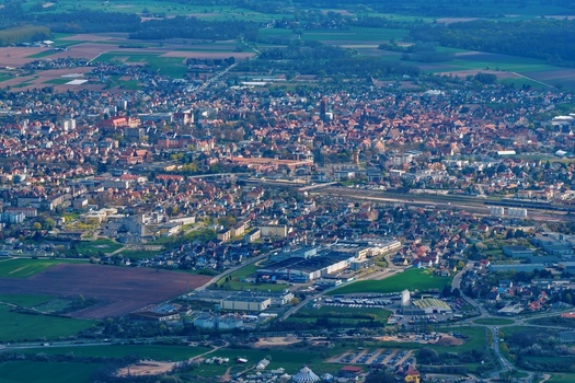 Aerial view of a sprawling cityscape nestled amid patchwork fields and verdant forests a symphony of urban and rural textures Kintzheim Grand Est France.