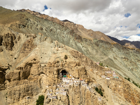 Aerial view of Phukthal Gompa a remote Buddhist monastery built into a cliffside cave surrounded by rugged Himalayan mountains and rocky terrain in Phukthal Ladakh India.