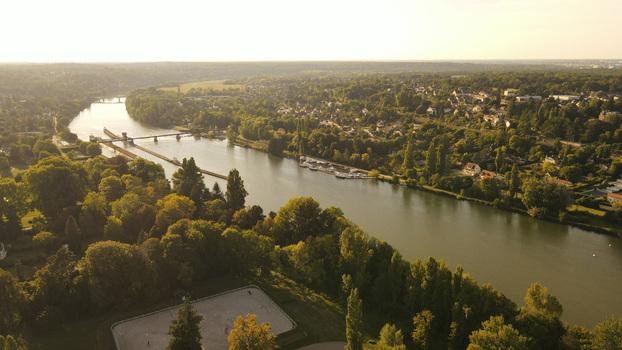 Aerial view of the Seine river winding through the green landscape of Chartrettes featuring a lock system small boats and dense forests. Chartrettes Ile de France France. Aerial view of the Seine river winding through the green landscape of Chartrettes featuring a lock system small boats and dense forests. Chartrettes Ile de France France.