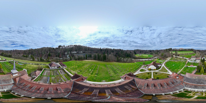 Aerial view of the Abbaye d Hauterive monastery complex featuring historic red tiled roofs lush green fields and surrounding forests in Hauterive Fribourg Switzerland.
