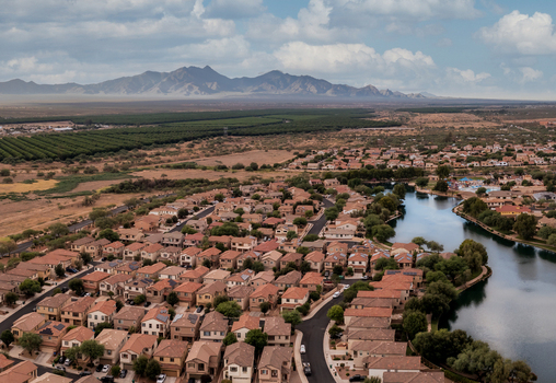 Aerial view of a residential neighborhood with houses and a lake surrounded by desert landscape and distant mountains in Sahuarita Arizona United States.