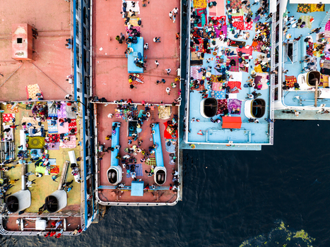 Aerial view of Sadarghat ferry terminal with passenger boats docked side by side crowded decks filled with people on colorful mats and Buriganga River water Dhaka Dhaka Division Bangladesh. Aerial view of Sadarghat ferry terminal with passenger boats docked side by side crowded decks filled with people on colorful mats and Buriganga River water Dhaka Dhaka Division Bangladesh.