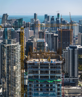 Aerial view of shimmering skyscrapers piercing the azure sky construction cranes painting yellow strokes against the urban canvas Miami Florida USA. Aerial view of shimmering skyscrapers piercing the azure sky construction cranes painting yellow strokes against the urban canvas Miami Florida USA.