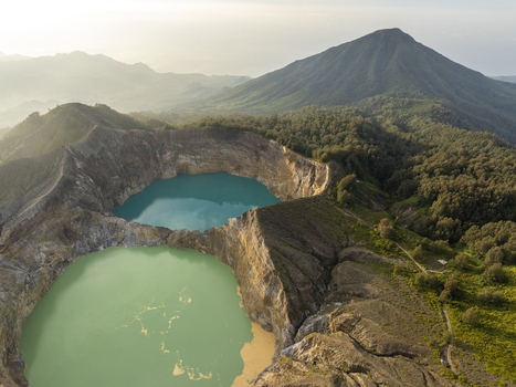 Aerial view of the turquoise and green volcanic crater lakes of Kelimutu National Park surrounded by rugged crater walls and lush forest in Detusoko East Nusa Tenggara Indonesia.