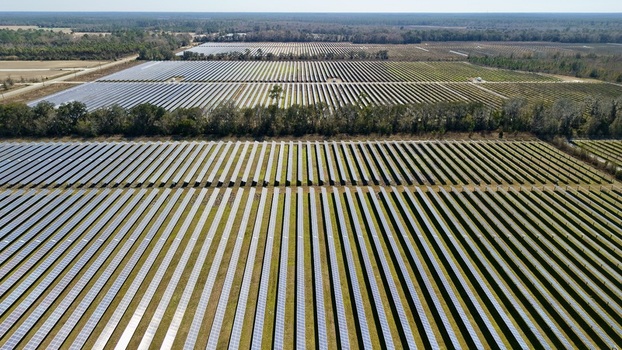 Aerial view of vast solar panel arrays gleaming under the sun contrasting with the surrounding green fields Elkton Florida United States. Aerial view of vast solar panel arrays gleaming under the sun contrasting with the surrounding green fields Elkton Florida United States.