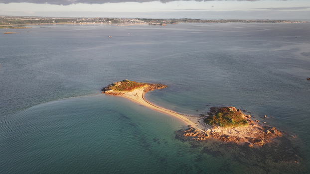 Aerial view of a sandbar pathway connecting two rocky isles in the tranquil azure sea Carantec Brittany France. Aerial view of a sandbar pathway connecting two rocky isles in the tranquil azure sea Carantec Brittany France.