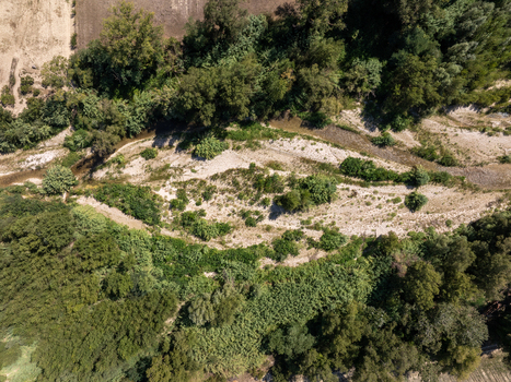 Aerial view of the Aso riverbed near Ortezzano featuring gravel banks lush green vegetation and trees along the riverbanks in Ortezzano Marche Italy. Aerial view of the Aso riverbed near Ortezzano featuring gravel banks lush green vegetation and trees along the riverbanks in Ortezzano Marche Italy.