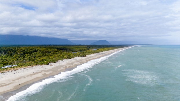 Aerial view of a pristine shoreline where the lush forest meets the turquoise ocean under a vast cloud dappled sky Ship Creek Haast West Coast Region New Zealand. Aerial view of a pristine shoreline where the lush forest meets the turquoise ocean under a vast cloud dappled sky Ship Creek Haast West Coast Region New Zealand.