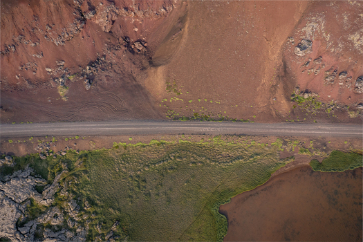 Aerial view of Ytri Raudarmelskula crater with a gravel road volcanic terrain green moss and a pond in Raudhamelur Eyja og Miklaholtshreppur Iceland. Aerial view of Ytri Raudarmelskula crater with a gravel road volcanic terrain green moss and a pond in Raudhamelur Eyja og Miklaholtshreppur Iceland.