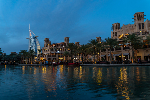 View of the Burj Al Arab and Madinat Jumeirah at dusk with traditional wind towers and palm trees reflected in the water Dubai Dubai United Arab Emirates. View of the Burj Al Arab and Madinat Jumeirah at dusk with traditional wind towers and palm trees reflected in the water Dubai Dubai United Arab Emirates.