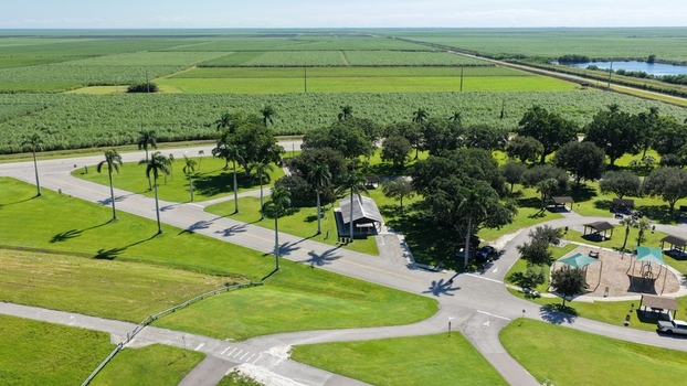 Aerial view of a park in Pahokee with palm trees a pavilion playground equipment and surrounding agricultural fields under a clear sky in Pahokee Florida United States.