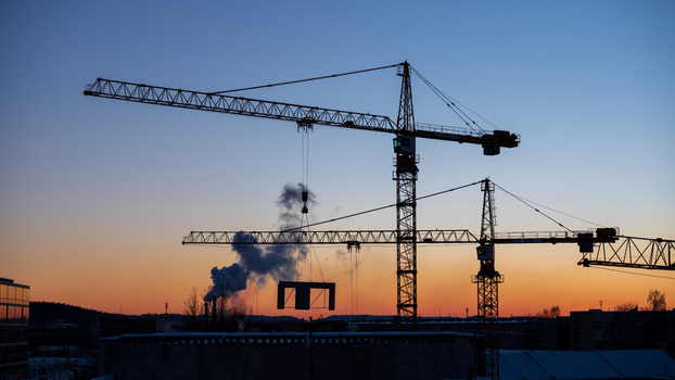 View of construction cranes silhouetted against a vibrant sunset sky at a building site in Vilnius Vilnius County Lithuania. View of construction cranes silhouetted against a vibrant sunset sky at a building site in Vilnius Vilnius County Lithuania.