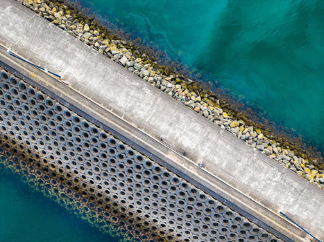 Aerial view of the concrete breakwater at Bangor Harbour featuring a textured sea wall with circular patterns and rocky embankments bordering the clear blue water in Bangor Northern Ireland United Kingdom.