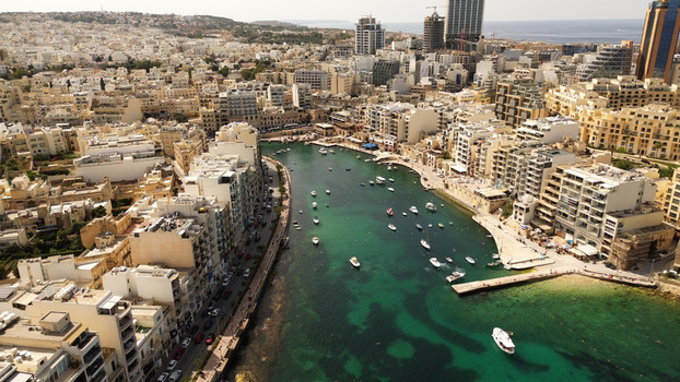 Aerial view of Spinola Bay with its turquoise waters small fishing boats and surrounding dense urban architecture in St. Julian s Malta. Aerial view of Spinola Bay with its turquoise waters small fishing boats and surrounding dense urban architecture in St. Julian s Malta.