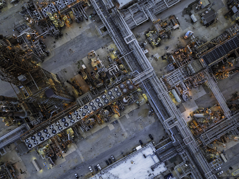 Aerial view of an oil refinery with a complex network of pipes industrial cooling fans and storage tanks illuminated by warm evening light Illinois United States.