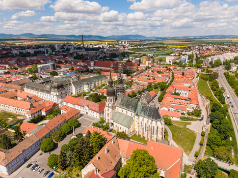 Aerial view of St. Nicholas Basilica surrounded by historic red roofed buildings lush green trees and the old city walls in Trnava Trnava Region Slovakia. Aerial view of St. Nicholas Basilica surrounded by historic red roofed buildings lush green trees and the old city walls in Trnava Trnava Region Slovakia.