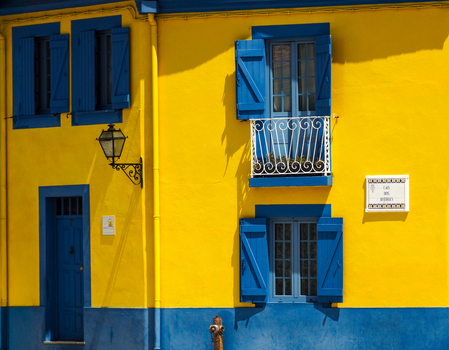 View of a bright yellow building facade with blue shutters and a small balcony in Aveiro Aveiro District Portugal.