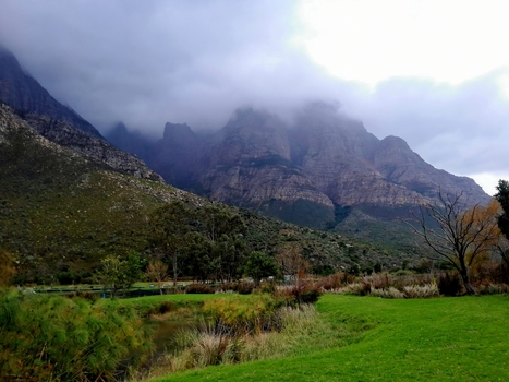 View of the rugged mountains of the Western Cape rising above a green valley with trees and grass in Montagu Western Cape South Africa.