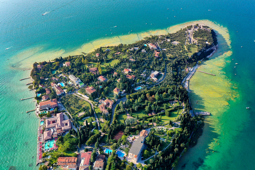 Aerial view of Villa Cortine and the lush peninsula surrounded by the turquoise waters of Lake Garda in Sirmione Lombardia Italy. Aerial view of Villa Cortine and the lush peninsula surrounded by the turquoise waters of Lake Garda in Sirmione Lombardia Italy.