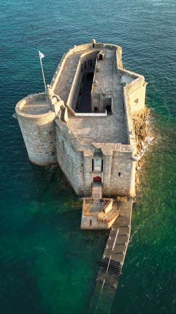 Aerial view of Chateau du Taureau a formidable stone fortress with rugged grey walls embraced by vibrant emerald waters Plouezoc h Bretagne France. Aerial view of Chateau du Taureau a formidable stone fortress with rugged grey walls embraced by vibrant emerald waters Plouezoc h Bretagne France.