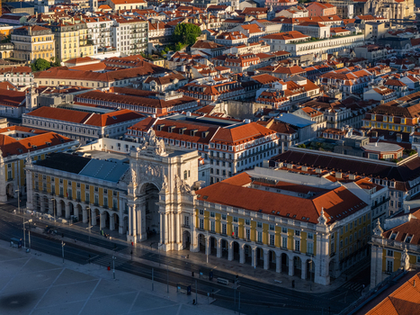 Aerial view of the Rua Augusta Arch and Praca do Comercio surrounded by historic red tiled rooftops and yellow buildings in Lisbon Lisbon Portugal. Aerial view of the Rua Augusta Arch and Praca do Comercio surrounded by historic red tiled rooftops and yellow buildings in Lisbon Lisbon Portugal.